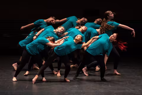 Students in blue shirts and black leggins perform artistic dance on stage at UAlbany Showcase Day 2024.