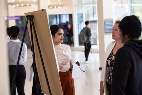 A student shows off her poster inside the UAlbany lecture center.