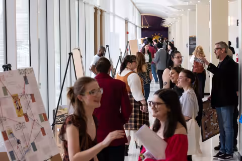 A large hallway in the lecture center concourse at UAlbany is filled with poster presentations and students and visitors talking during Showcase Day 2024.