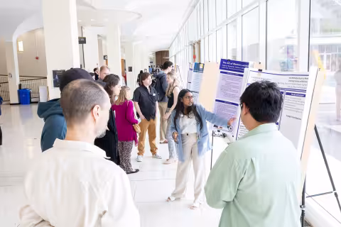 A student presents her work inside the Lecture Center as several guests listen during Showcase Day 2024.