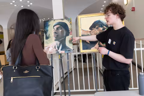 A student discusses his artwork with a visitor during Showcase Day 2024.