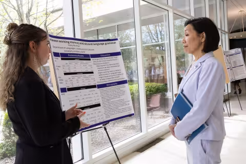 A student explains her research to UAlbany Provost Carol Kim during Showcase Day 2024 inside the Lecture Center concourse.