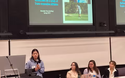 A student stands and gives a presentation on trans-masculine athletes while presenting on a panel at UAlbany Showcase