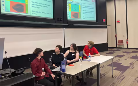 A student sits and holds a microphone while presenting on the vibrator as a symbol on a panel at UAlbany Showcase