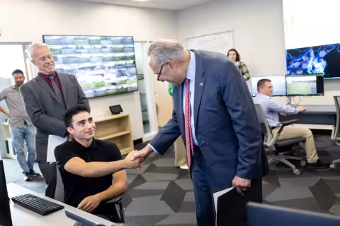 Senator Schumer shakes hands with a student inside the NYS Mesonet operations center.