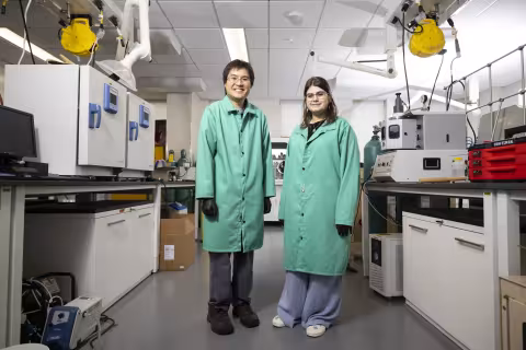 Alma Kolakji stands with her summer mentor inside a lab research space.