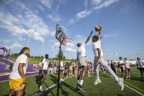 Members of UAlbany’s men’s basketball team demonstrate their skills with a hoop set up on the football field during Great DANEtopia. 