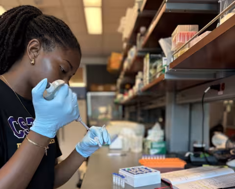 Zyon Small holds a test tube inside a lab at UAlbany.