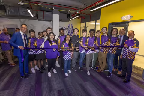 UAlbany Esports students stand with campus leaders to cut a purple ribbon in the arena.