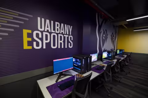 Gaming PCs in front of a UAlbany Esports graphic inside the new arena.