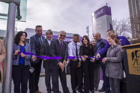 Havidán Rodríguez at the CDTA Purple Line ribbon cutting with big scissors.