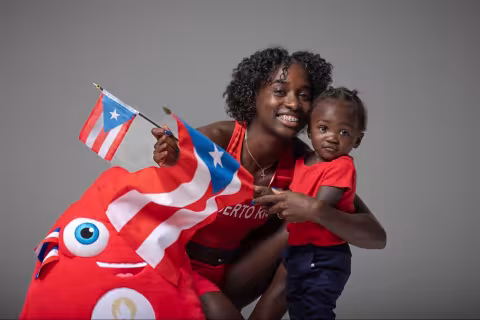 UAlbany alum Grace Claxton waves a Puerto Rican flag while embracing her son, Thyree.