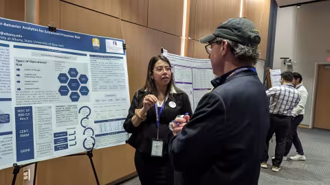 Student talking about her project in front of a poster.