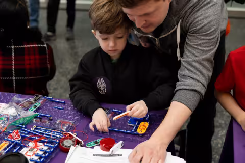 A child and his father work together on an engineering project at the STEM and Earth Sciences Family Day.
