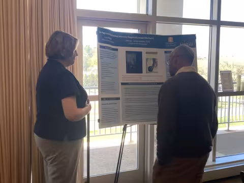 Attendees look at student poster presentation.
