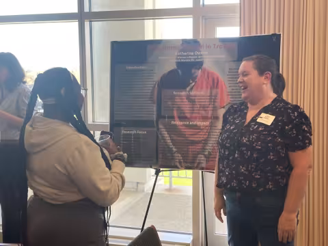 Student presenting and speaking with attendee.