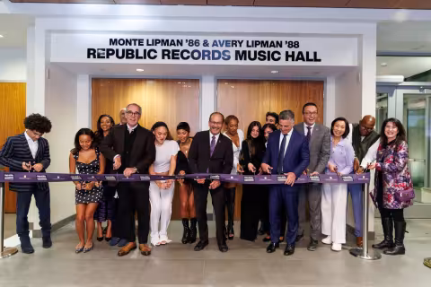 A large group of people stand for a ribbon cutting in front of an auditorium that reads the Monte and Avery Lipman Republic Records Music Hall.