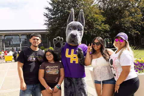 Student and family pose with UAlbany's Damien