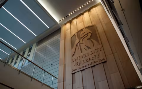 A building wall features and image of Minerva and the words "University at Albany State University of New York