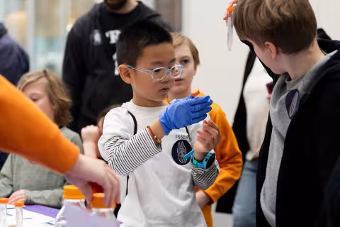 Children hold up science vials in the ETEC atrium during STEM and Earth Sciences Family Day.