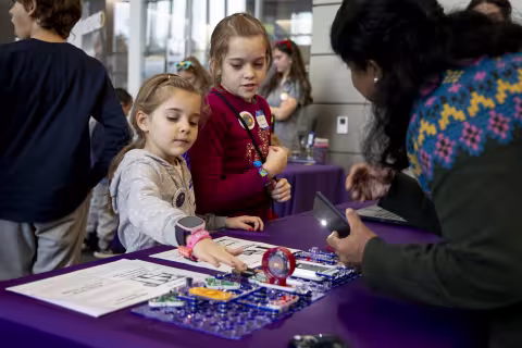 Two children interact with CEHC makerspace students at the Lego challege event.