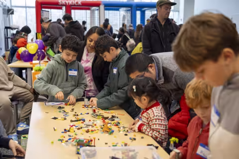Children and their parents build legos on a table at the ETEC atrium.