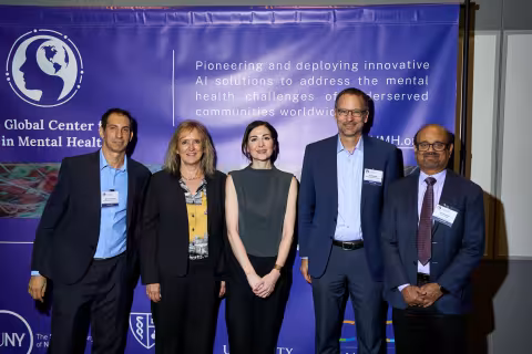 Five people pose for a photo in front of a GCAIMH Annual Summit banner.