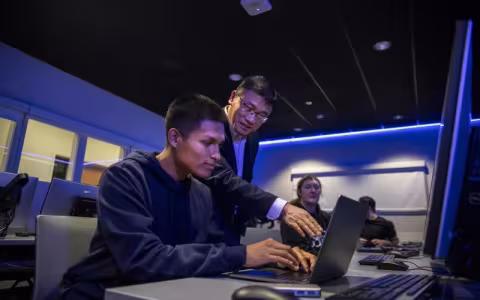 Cybersecurity professor Alan Wang works with a student on his class project from the Cyber Range lab.