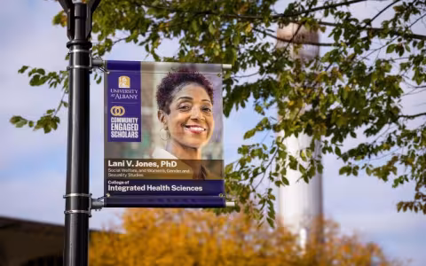 a banner on a post shows a smiling woman and the words University at Albany Community Engaged Scholars/ Lani V. Jones PhD/ College of Integrated Health Sciences