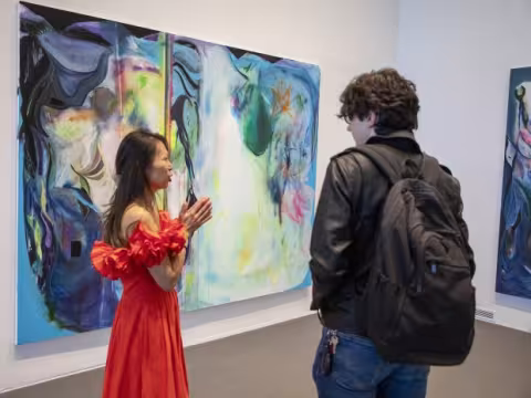 Student talking with an artist in front of a large painting.