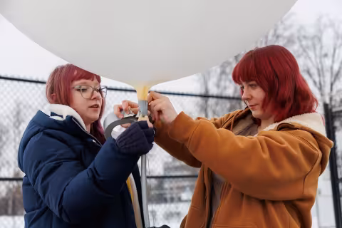UAlbany students attach a radiosonde to the weather balloon ahead of its launch.