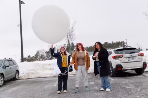 UAlbany students hold a weather balloon up in the air and prepare it for launch.