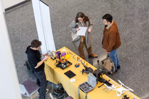 Aerial view of people gathered around a table topped with various technology