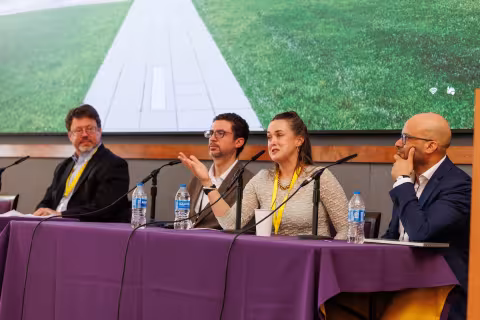 A woman speaks into a microphone as part of a panel discussion