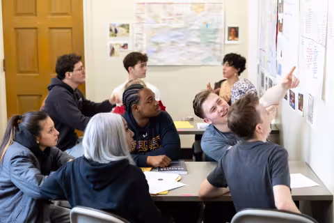 An image of four students looking up at information on a white board.