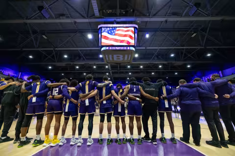 UAlbany basketball players lined up with their arms around each other before the Big Purple Growl Game.