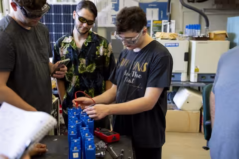 People in safety glasses gather in a laboratory for a training on energy storage technologies