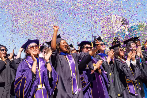 A group of students at the graduate ceremony celebrating in confetti.