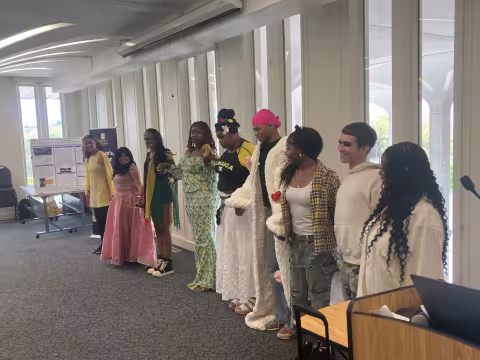 Nine students holding hands standing next to each other.