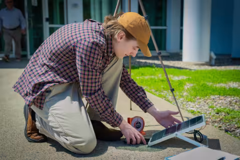 A young man gathers around a solar panel for a workshop on energy storage technologies