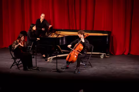 Three students playing a piano, cello and flute perform a song at Showcase.