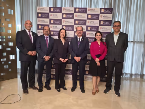 Six UAlbany officials stand in a row and smile for photo in front of a backdrop with the UAlbany and RISM logos.