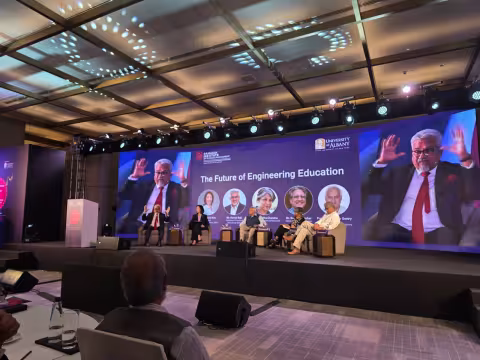Five officials from UAlbany and RISM sit on stage and engage in a panel discussion. Behind them, a screen shows their names, titles and photos, as well as the words, "The Future of Engineering Education."