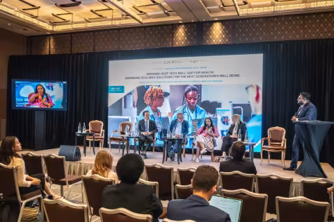 Dr. Amy Nitza, Director of the Global Center for AI in Mental Health (GCAIMH) (rightmost seated participant) presents TherAssist during a panel discussion on the role of AI.