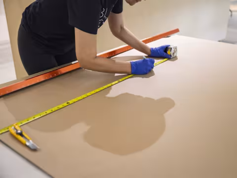 Gloved person measuring cardboard