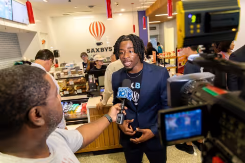 The student CEO of Saxbys inside the Massry School of Business Theo Rhynie is interviewed by a TV station 