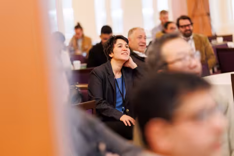 An audience member listens intently during a presentation at the 2026 AI Plus Symposium.