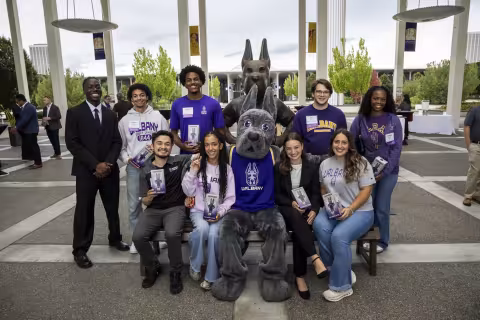 UAlbany students pose for a photo with the Damien statue.