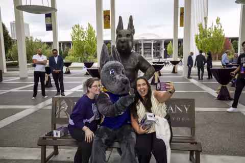 UAlbany's Director of Marketing and Social Media Manager pose for a photo with the new Damien statue.
