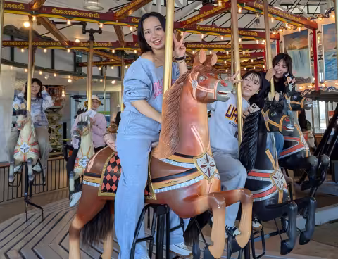 Five students smile as they ride an antique carousel.